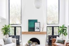 a modern Spanish space with white walls, a faux fireplace, warm-colored furniture and bright touches and prints