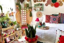a super colorful boho bedroom with decorative plates, potted plants, colorful tassels and throws plus pompoms for decor