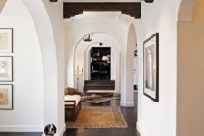 white plaster walls paired with dark floors and dark wooden beams plus arched doorways look very Spanish-like