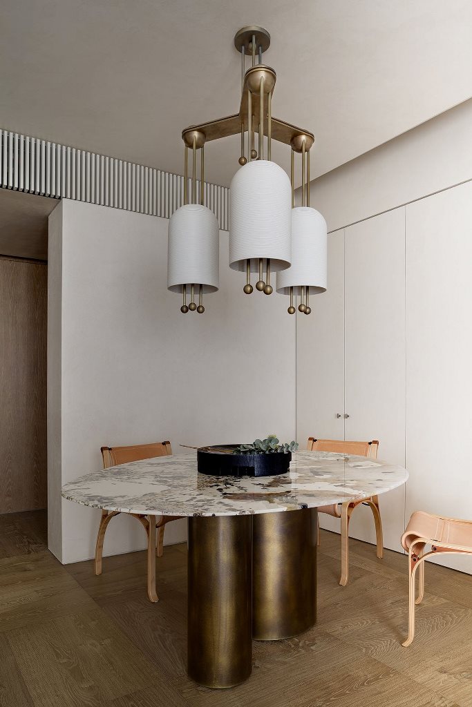 The dining space features a unique table with a stone tabletop, leather chairs and a bold chandelier