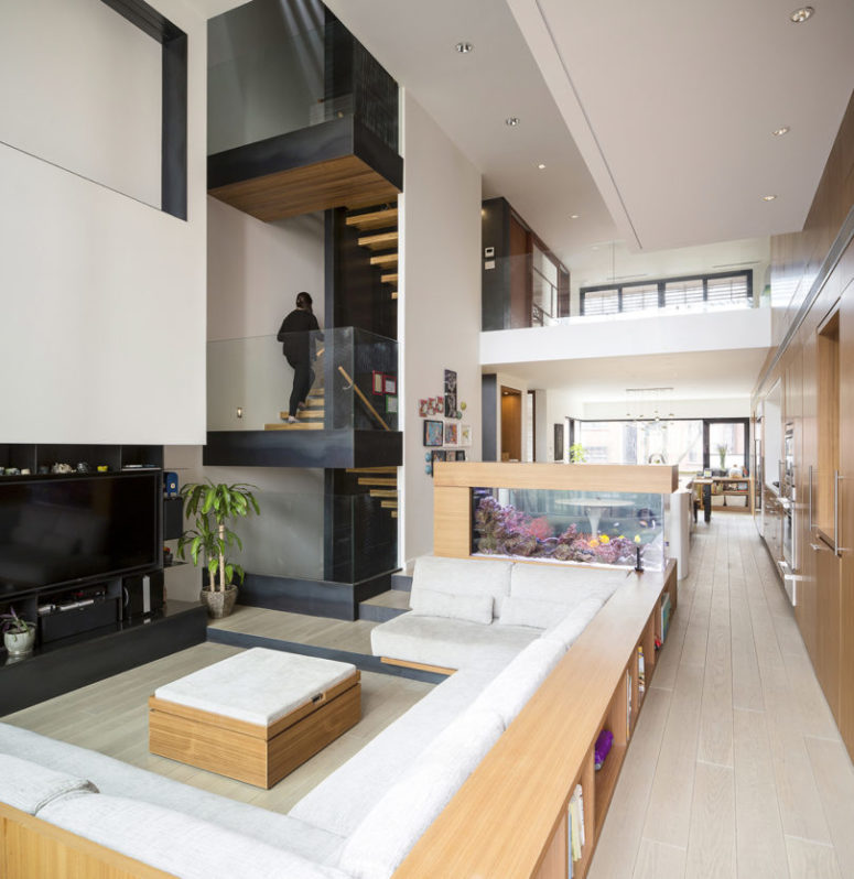 The living room is done with a sunken conversation space, with wooden furniture and a TV