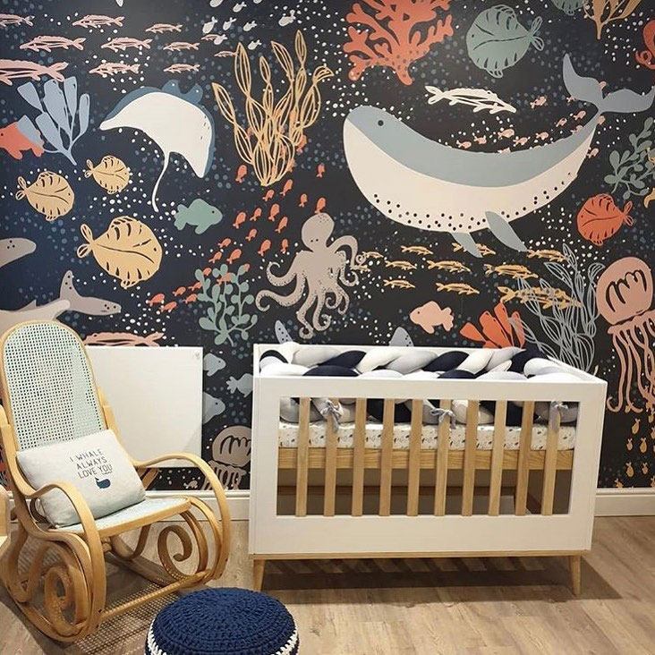 dark and moody sea life wallpaper for a statement wall, a navy pillow and a cute whale one on the chair