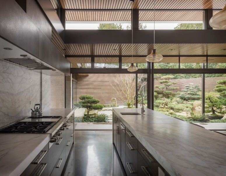 The kitchen is done with dark cabinets, white stone countertops and lots of light from double-height ceilings