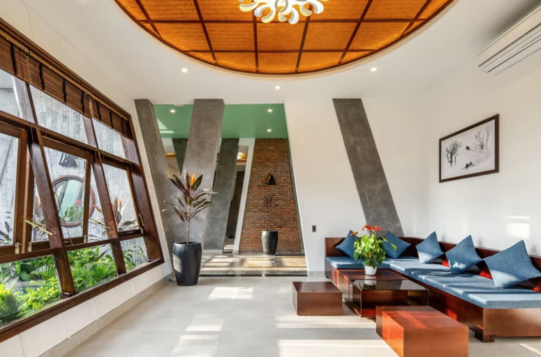 The living room is minimal yet done in bright colors, with rich stained wooden furniture and window frames plus blue upholstery