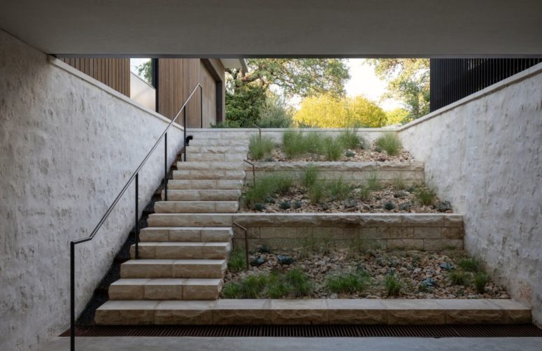 The wood-clad volumes sit on a limestone plinth which is carved out to reveal an underground area