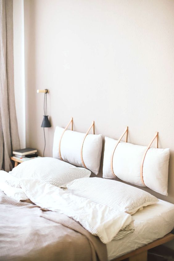 a neutral peaceful space with a headboard composed of two pillows hanging on leather