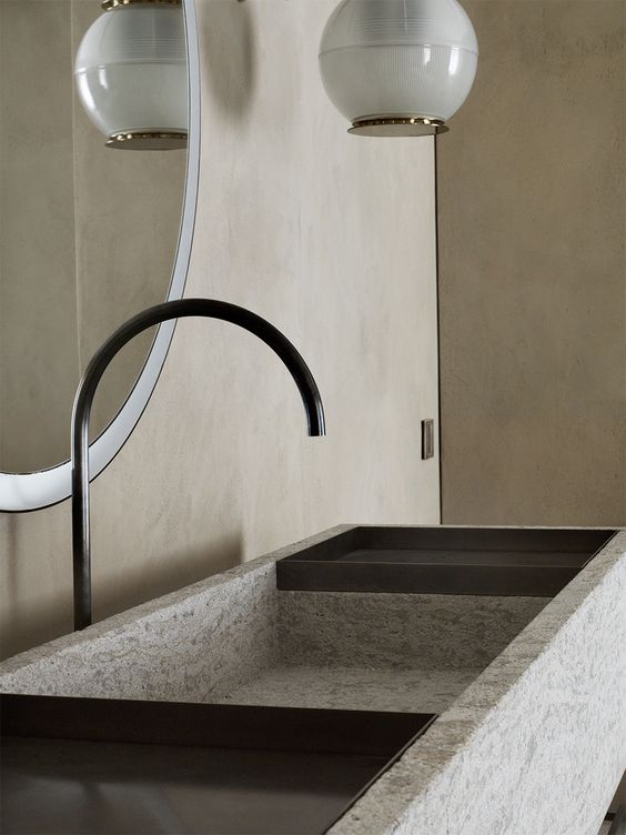 The bathroom is done with neutral plywood panels, with a textural stone sink and an elegant pendant lamp