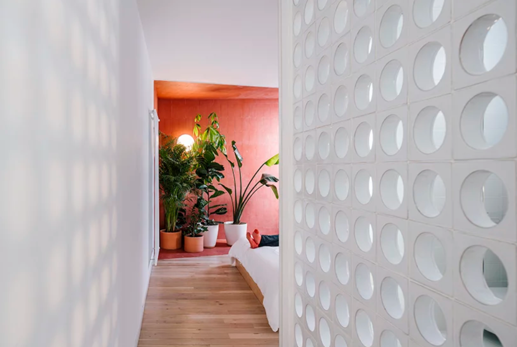 The bedroom is separated with a perforated wall and features a red color blocked zone