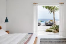 06 The bedroom is white, there’s simple yet chic woodne furniture, blue lamps and an entrance to the terrace