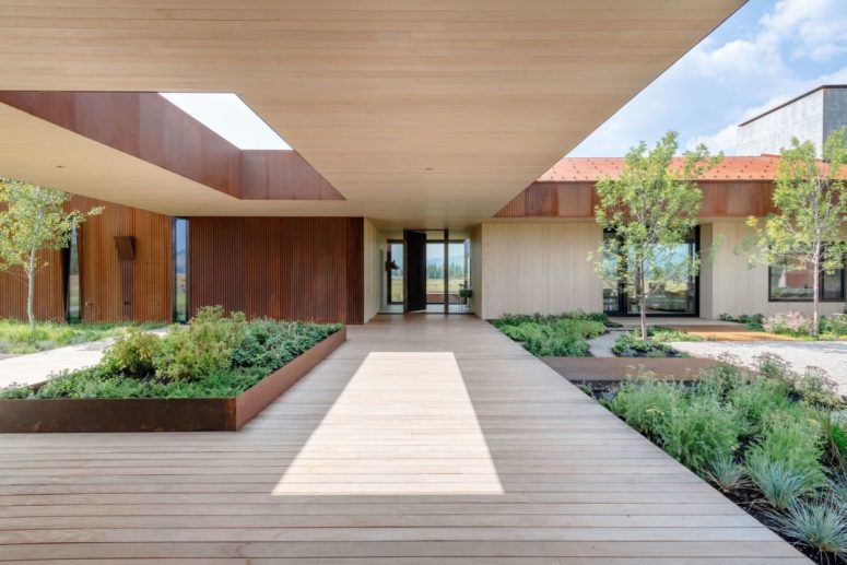 The house features large openings under the roof to fill the spaces with greenery and connect indoors with outdoors