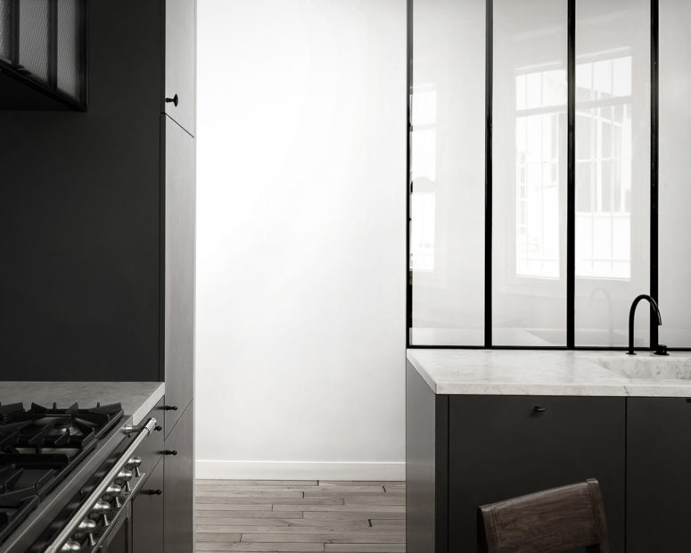 The kitchen is done with dark cabinets, white stone countertops and black frames plus frosted glass