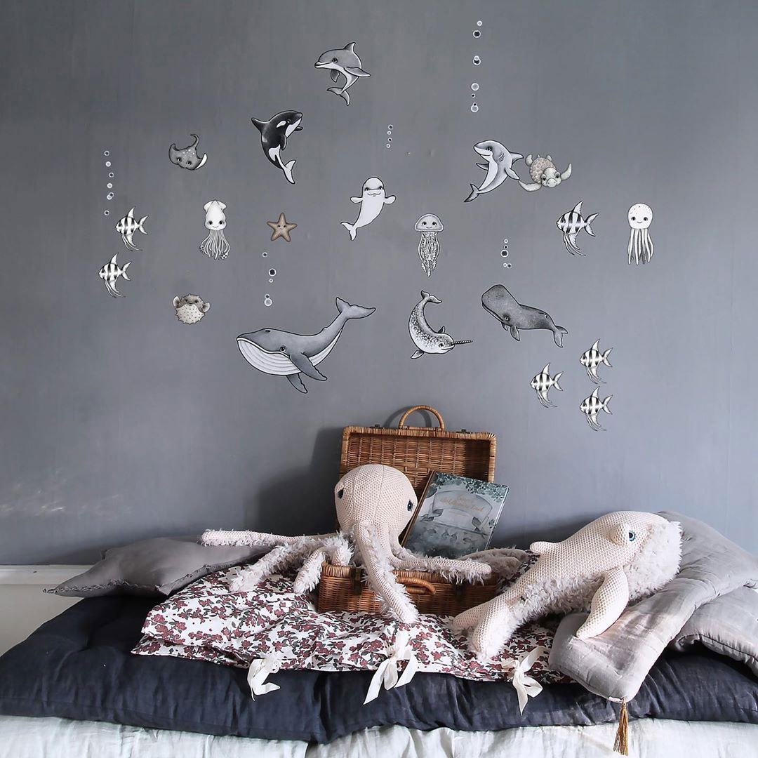 a grey nursery with a sea creature statement wall and some cute sea life plush toys