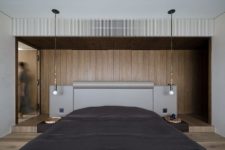 07 The contemporary bedroom is clad with wood, there are bulbs and an upholstered bed