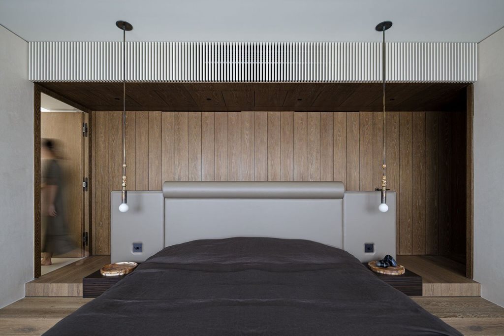 The contemporary bedroom is clad with wood, there are bulbs and an upholstered bed