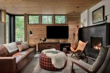 07 The space is done with a leather sofa, a fireplace, some glazings and natural wood covering the walls