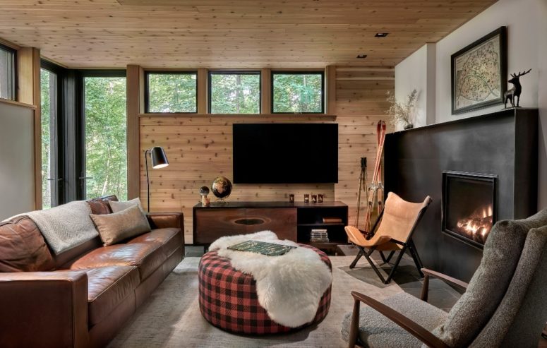 The space is done with a leather sofa, a fireplace, some glazings and natural wood covering the walls