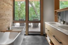 08 The bathroom is done with dark tiles, lots of wood, a double vanity and a sculptural bathtub