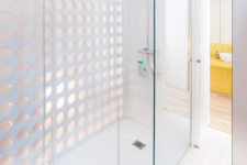 08 The shower space is all-white, with a perforated wall on one side