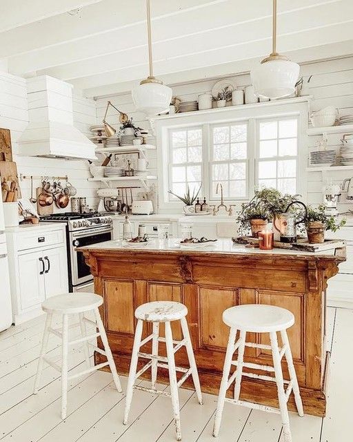 a pure white kitchen with a warm colored vintage kitchen island with a strong rustic feel at the same time