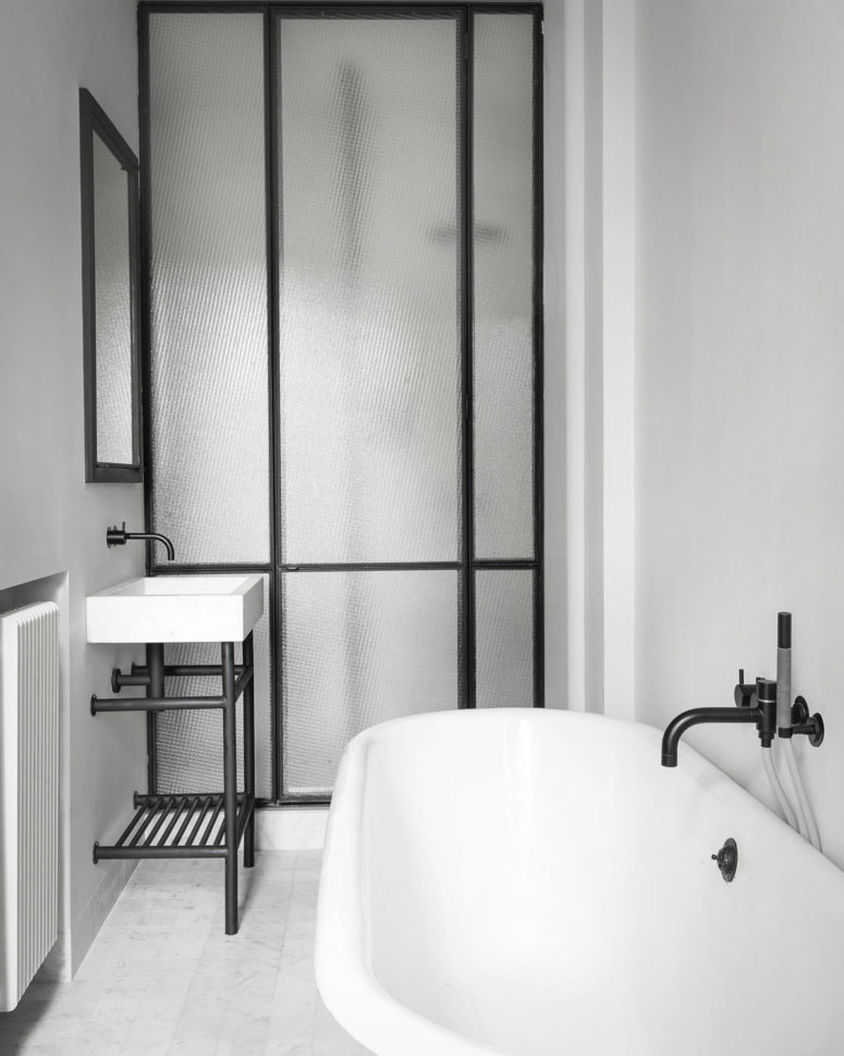 Another bathroom is done with white appliances, black fiixtures and the same black framed frosted glass