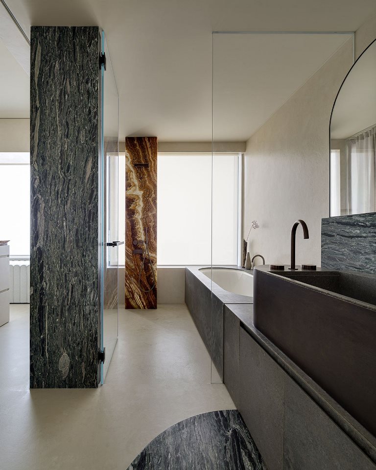 The bathroom is done with a tub covered with stone and a stone stink plus gorgeous marble pillars