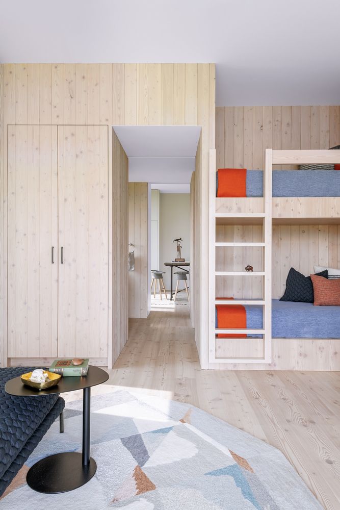 The guest bedroom is again clad with the same light-colored wood, there's a bunk bed and some bright touches