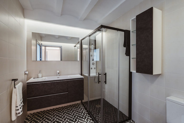 The second bathroom is done in black and white, with printed tiles and a shower space