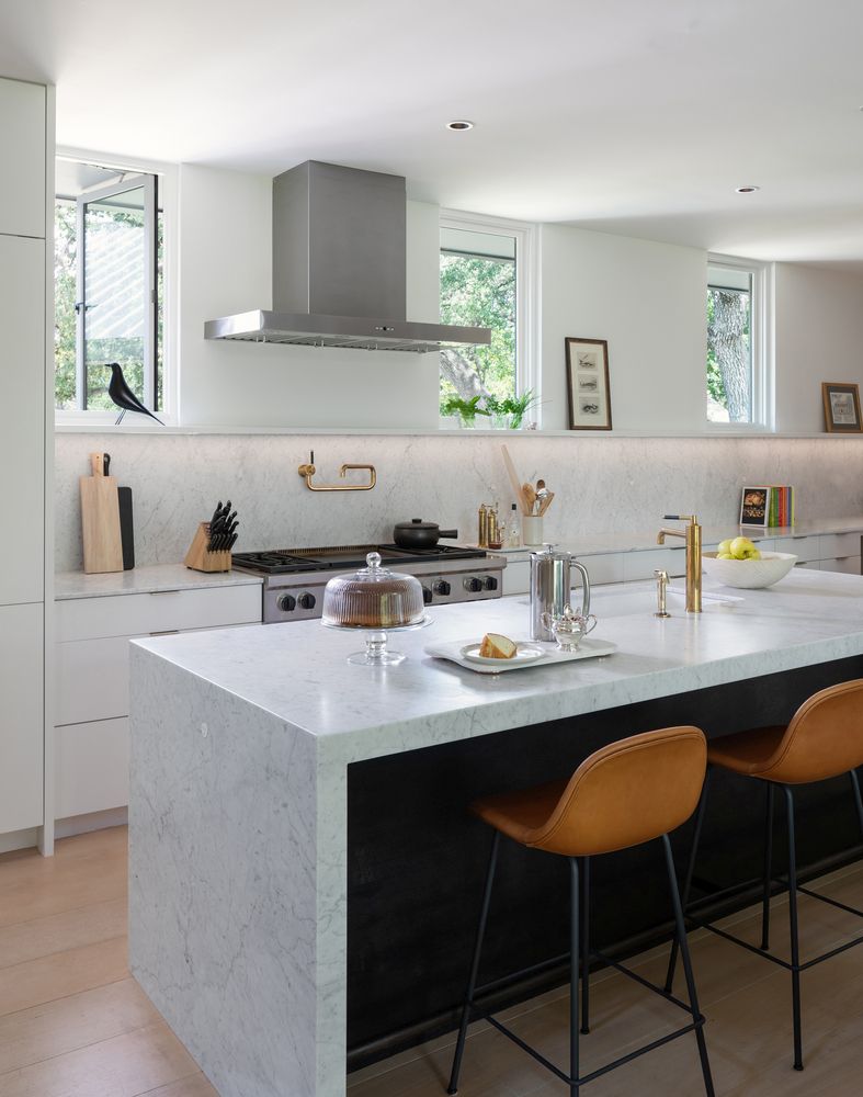 The kitchen is neutral and very airy, with stone countertops, leather stools and touches of gold here and there