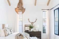 13 a neutral eclectic bedroom with wooden beams on the ceiling, a statement brass chandelier with candles