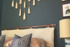 14 a boho bedroom with a black statement wall, a tassel hanging, a neutral cushion headboard on a copper holder