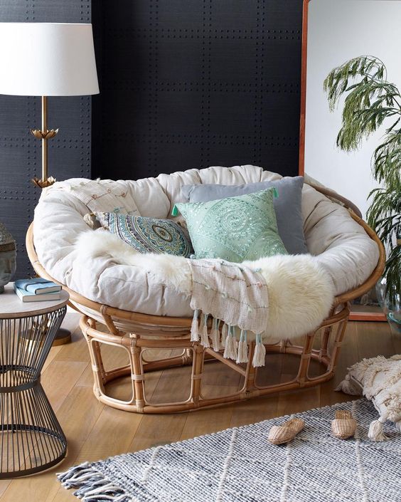 a gorgeous rattan mamasan chair with a neutral futon and pastel and printed pillows for a neutral boho space