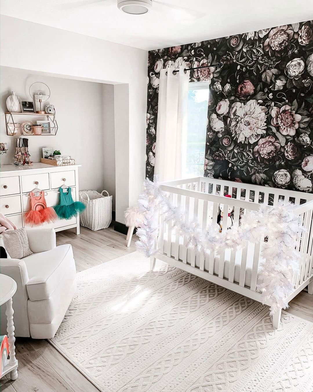 a gorgeous kid's nursery with a refined black realistic floral print wall that stands out in a white space