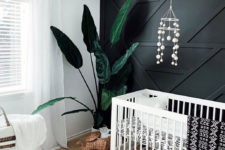 20 a boho nursery with a black geometric accent wall that stands out and make the whole space more stylish