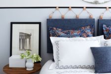 20 a hanging headboard made of blue denim on amber leather holders and a matchign denim pillow on the bed