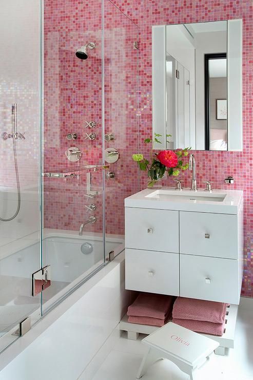 a small yet contrasting bathroom done in pink and white, with a statement wall and matching towels