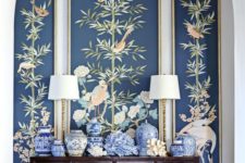 21 an entryway with a console, blue vases, lamps and dark flora and fauna wallpaper for a statement