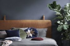 22 a moody bedroom in black refreshed with a potted plant, bright pillows and a leather hanging headboard for a statement