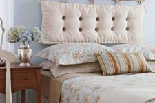 24 a vintage-inspired bedroom in pastel blues, tan and creamy, with a cushion headboard hanging on a small shelf