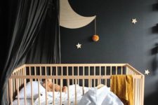25 a cute celestial nursery with a black statement wall and a black cnaopy over the crib to make the space peaceful