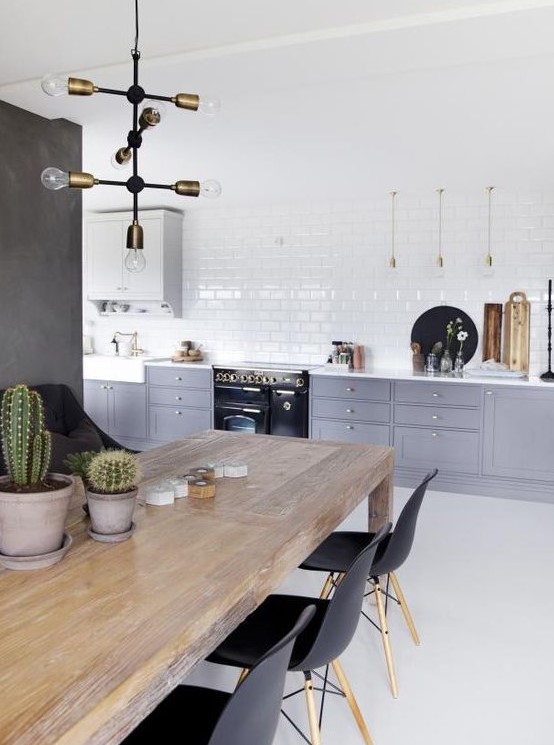 a Scandinavian kitchen with grey and white cabinets, white subway tiles, a wooden table and black chairs is very fresh