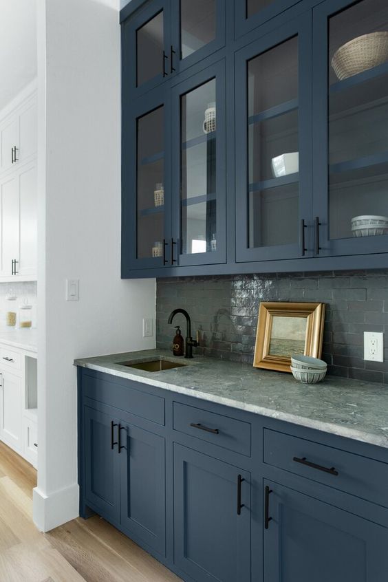 a beautiful and refined navy kitchen with a black tile backsplash and a grey stone countertop plus black fixtures is super chic