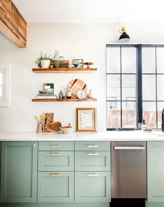 a beautiful sage green kitchen with white stone countertops, open shelves, rich stained touches and gold handles is very chic