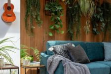a biophilic living room with potted plants suspended over the sofa to the natural wooden wall