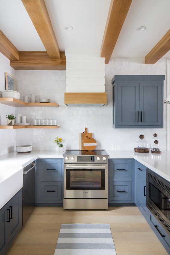 a blue and white farmhouse kitchen with wooden beams and open shelves plus a white square tile backsplash