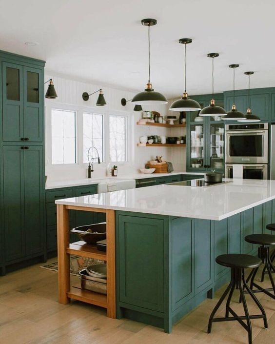 a bold green kitchen with shaker style cabinets, white stone countertops that echo with white walls, black pendant laps and sconces