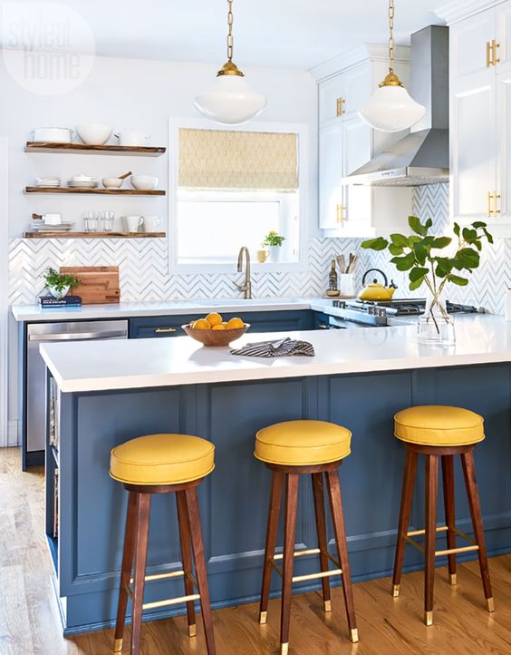 a bright kitchen with navy cabinets, white countertops and a chevron backsplash plus touches of brass and gold