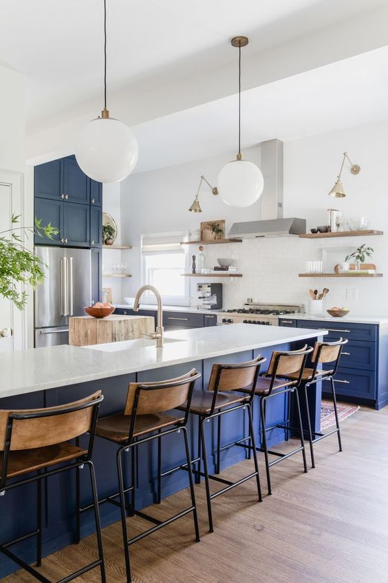 a bright modern kitchen with bold blue lower cabinets and a kitchen island, white countertops and a backsplash