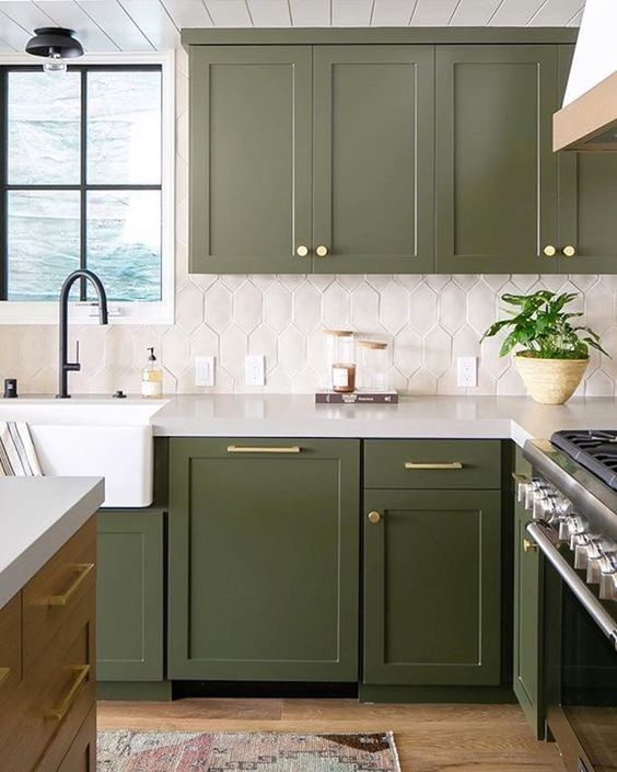 a catchy green kitchen with a white tile backsplash and gold touches plus black fixtures is super stylish