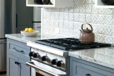 a chic blue and white kitchen with a grey countertop and a grey tiel backsplash looks neat, stylish and timeless
