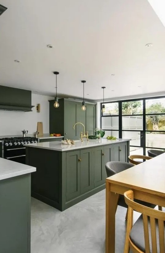 a chic contemporary kitchen with dark olive green cabinets, white countertops, a black cooker and bulbs over the kitchen island